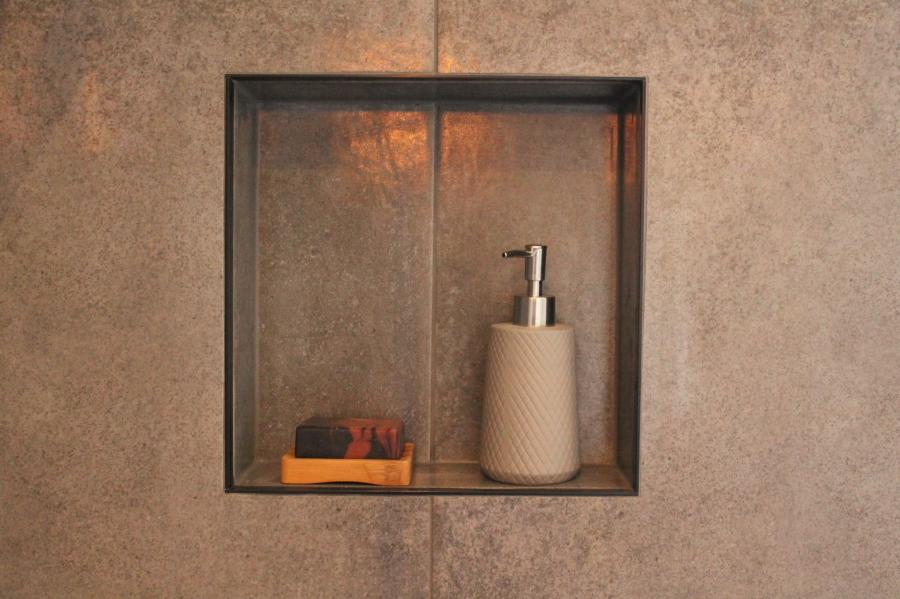 Built-in shower niche with soap dispenser and bar soap in textured tiled bathroom wall