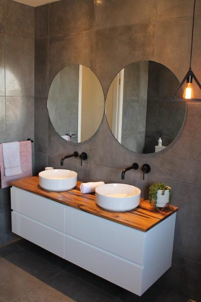 Modern bathroom vanity with double vessel basins, round mirrors and timber benchtop