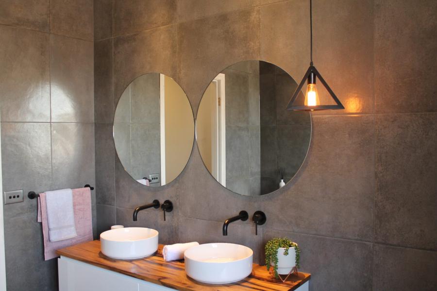 Modern bathroom vanity with double basins, round mirrors and warm pendant light