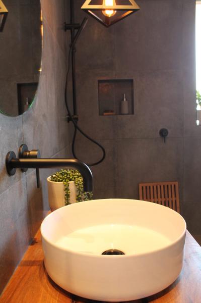 Round white vessel basin on timber vanity in a modern grey tiled bathroom