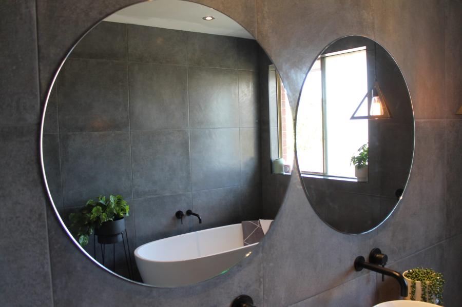 Modern bathroom with round mirrors, freestanding basin and dark textured walls