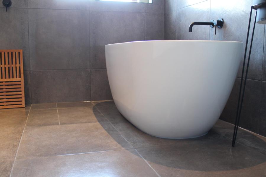 Freestanding white bath in a modern grey tiled bathroom