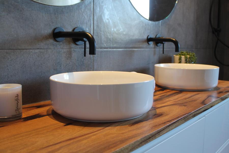 Double white vessel basins on timber vanity with black wall taps in a modern bathroom