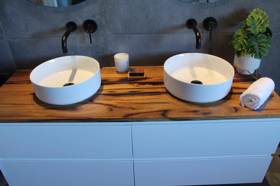 Double vessel basins on timber vanity with black wall taps in a modern bathroom