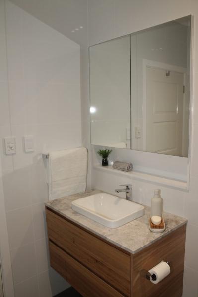 Timber bathroom vanity with stone benchtop, basin sink and mirrored cabinet