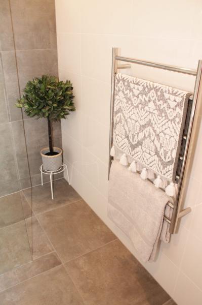 Heated towel rail with patterned towel in a modern tiled bathroom corner