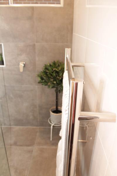 Walk-in shower with grey wall tiles, glass screen and towel rail in a modern bathroom