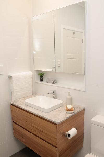 Compact bathroom vanity with timber drawers, stone benchtop, mirror cabinet and square basin