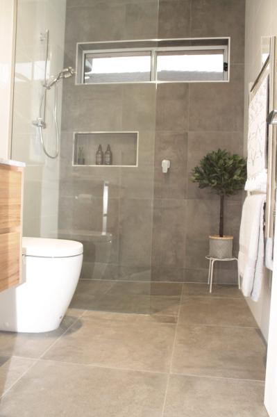 Modern walk-in shower with grey tiles, niche, toilet and timber vanity in a contemporary bathroom