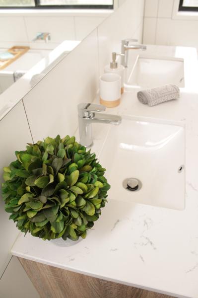 Modern white bathroom vanity with basin, chrome tapware and decorative greenery
