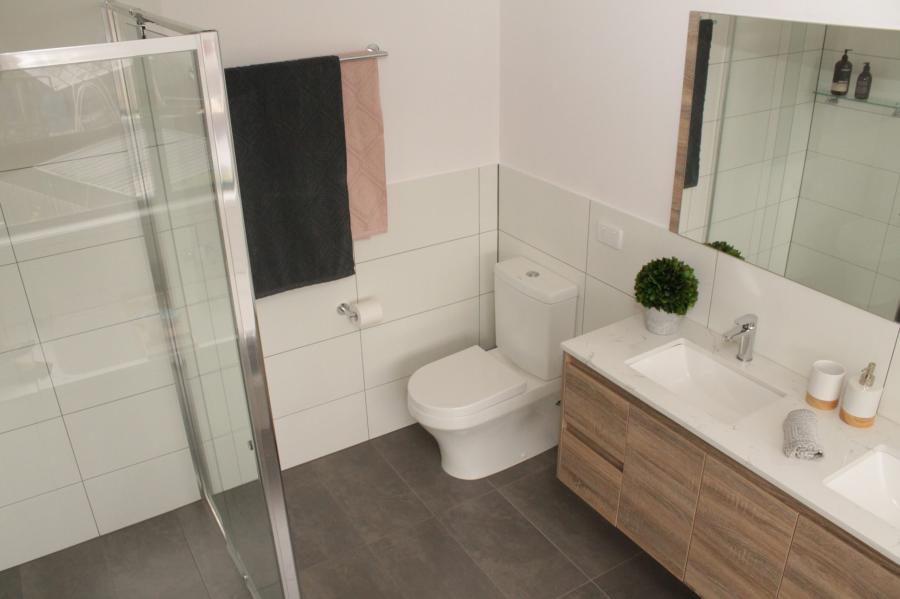 Modern bathroom with glass shower, wall-hung vanity, toilet and large mirror