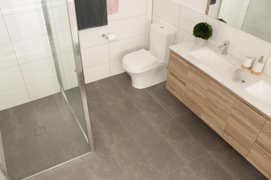 Modern bathroom with glass shower, timber vanity and grey floor tiles
