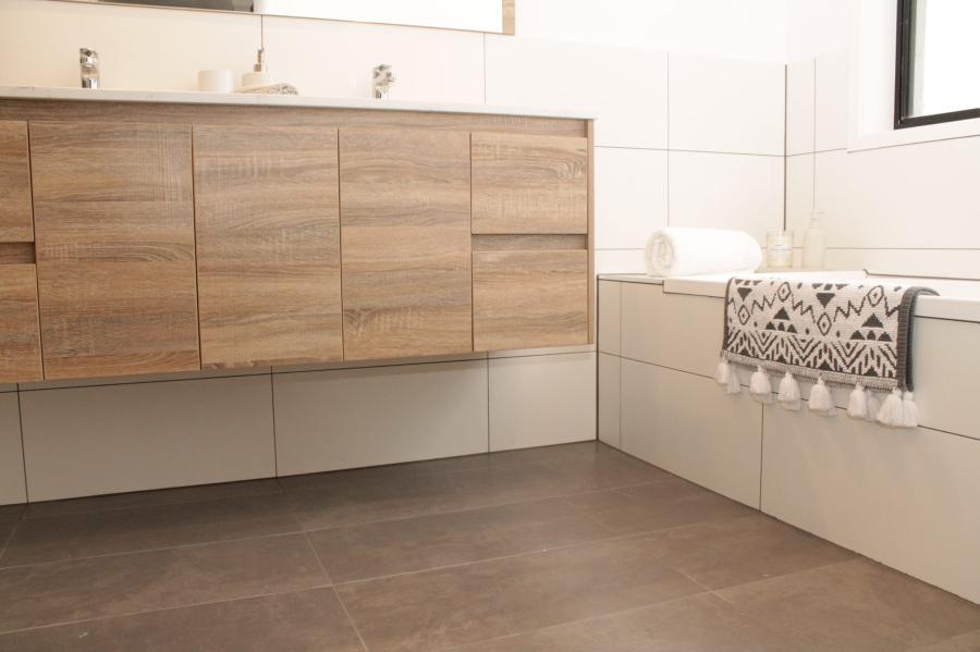 Floating timber vanity in a modern white tiled bathroom with patterned hand towel
