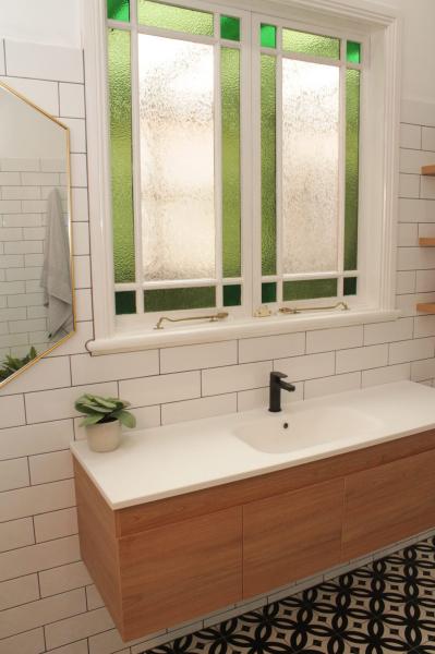 Modern bathroom vanity with green-framed frosted window and white subway tiles