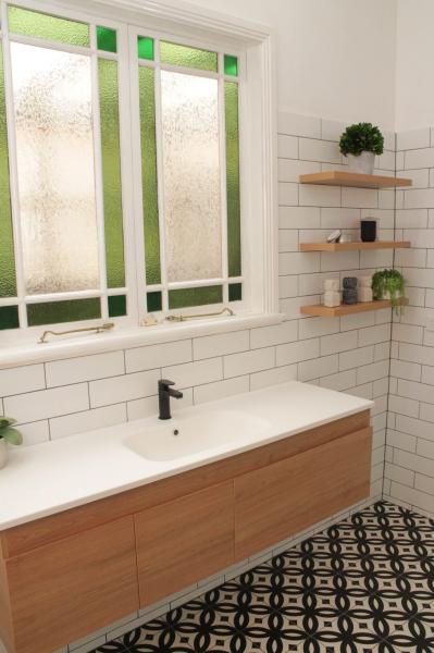 Modern bathroom vanity below frosted window with subway tiles and patterned floor