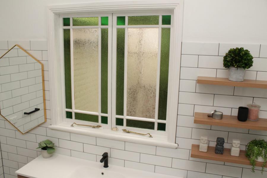 White tiled bathroom with frosted window, black tap and timber wall shelves
