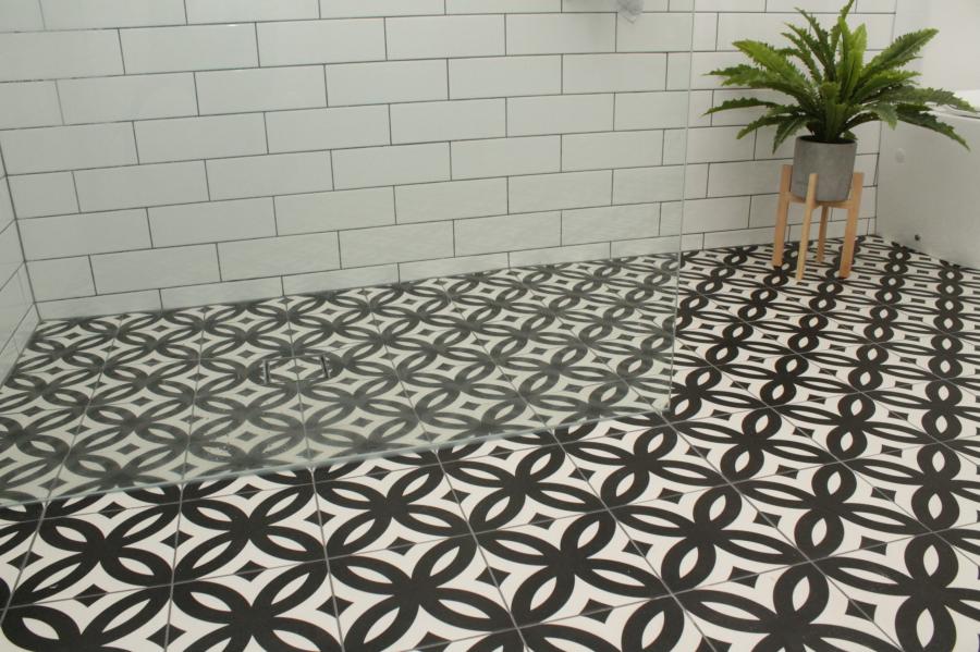 Black and white patterned floor tiles with white wall tiles and potted plant