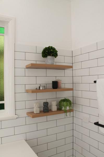 Bathroom corner with white subway tiles and floating timber shelves