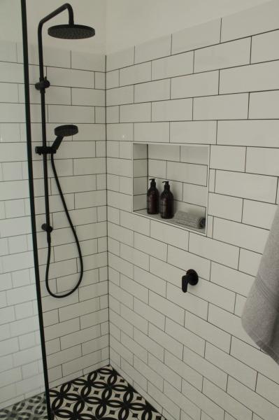 Walk-in shower with white subway tiles, black tapware and recessed niche