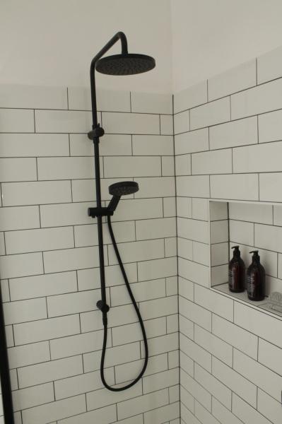 Black shower set in white subway tiled shower with recessed niche