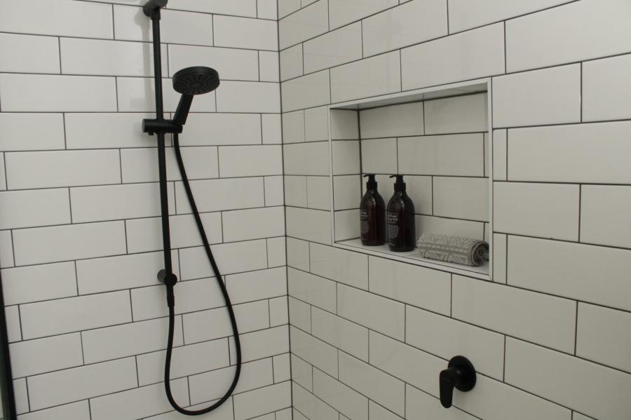 White tiled shower with black shower rail and recessed niche