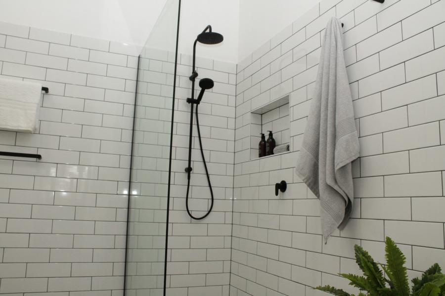 Modern walk-in shower with white subway tiles, black shower fitting and recessed niche