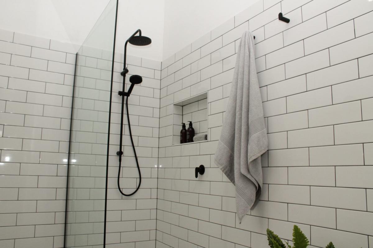 Modern bathroom shower with black tapware and white subway tiles