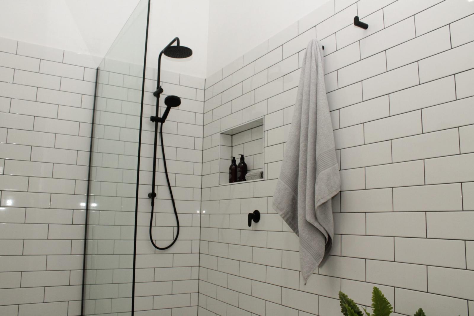 Modern bathroom shower with black tapware and white subway tiles