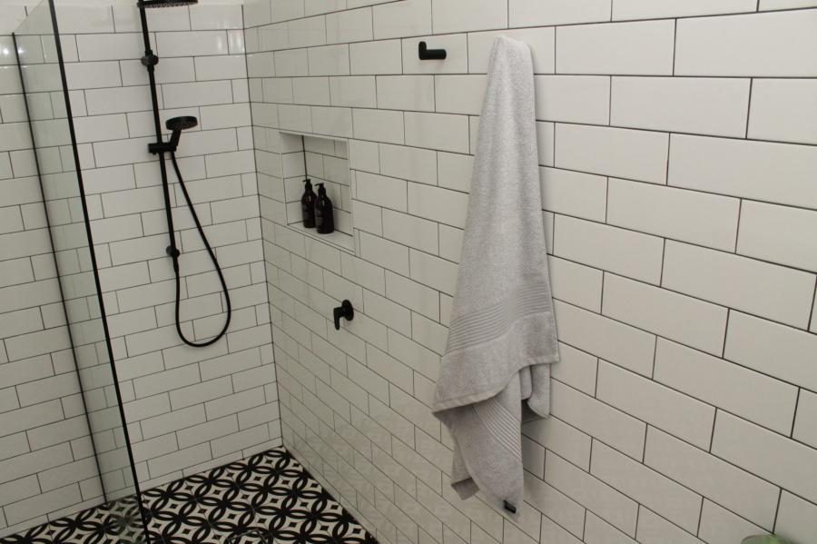 Walk-in shower with white subway tiles, black fittings and patterned floor tiles