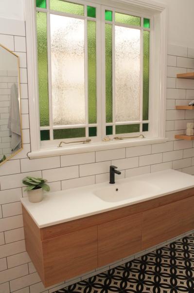 Timber wall-hung bathroom vanity beneath frosted window with white subway tiles
