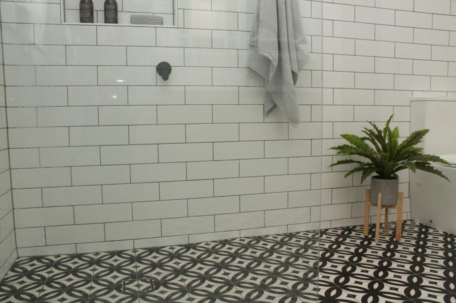 Walk-in shower with white subway tiles and patterned floor tiling