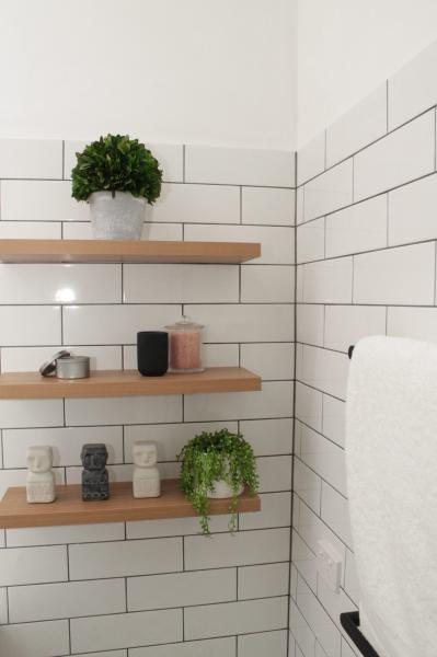 Bathroom wall shelves with white subway tiles, plants and neatly arranged toiletries