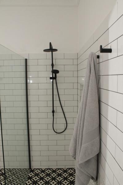 Walk-in shower with white subway tiles, black fixtures and patterned floor tiles