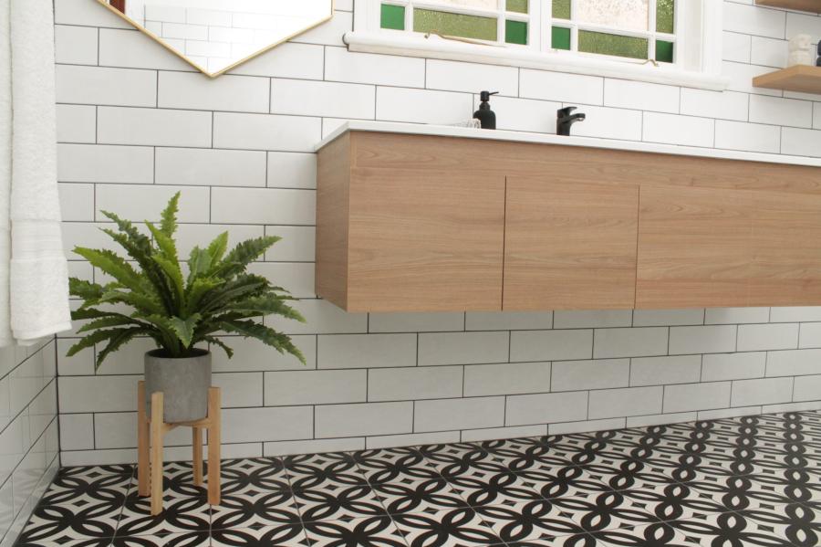 Floating timber vanity in a white tiled bathroom with patterned floor tiles