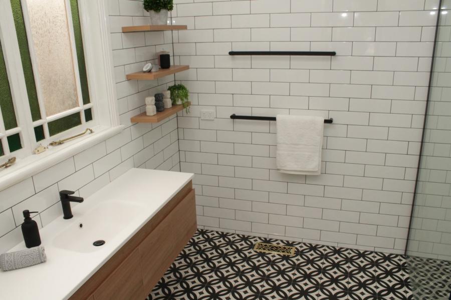 Walk-in shower with white subway tiles, patterned floor tiles and timber vanity