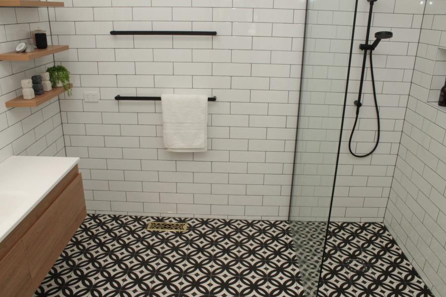 Modern walk-in shower with white subway tiles and patterned floor tiles