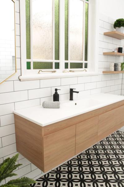 Floating timber vanity with black tapware beneath a frosted window in a bright modern bathroom
