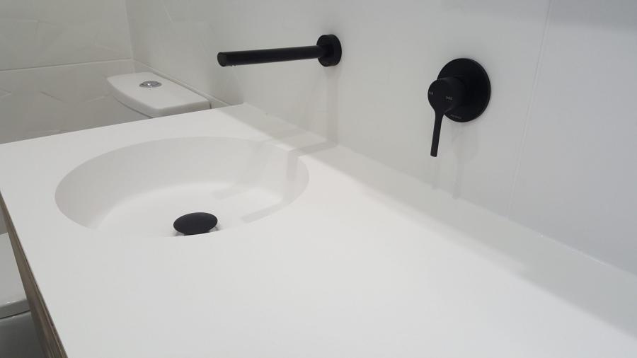 White bathroom vanity with integrated basin and matte black wall-mounted tapware