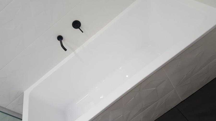White freestanding bath with matte black wall-mounted taps in a modern bathroom