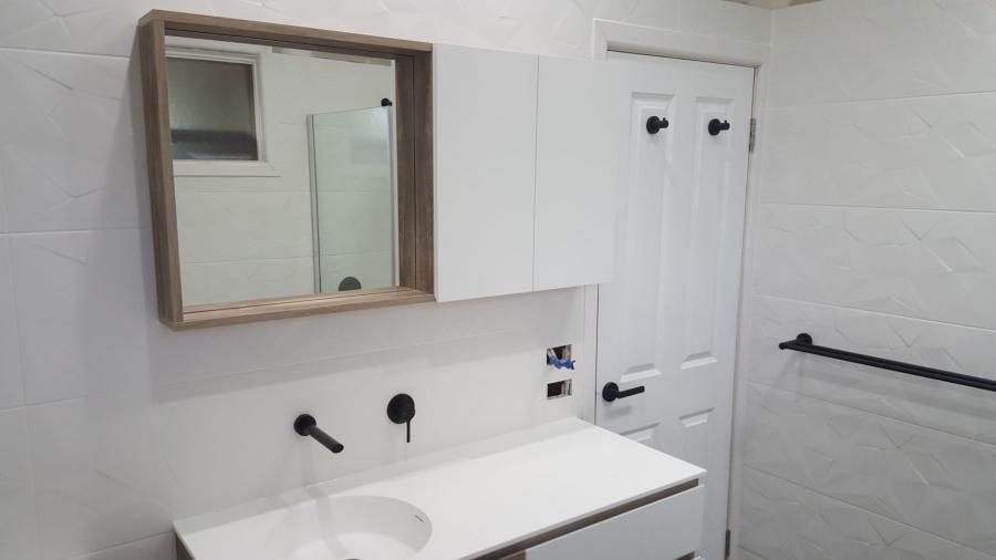 Modern white bathroom vanity with mirrored cabinet, black tapware and towel rail