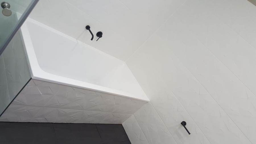White rendered bathroom wall with protruding boxed bulkhead and plumbing points