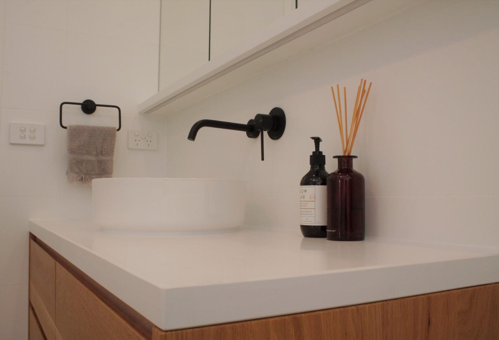 Modern bathroom vanity with black tapware and white stone countertop