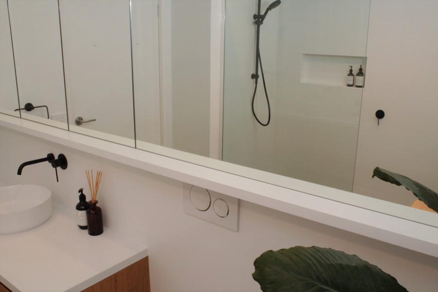 Modern white bathroom vanity with mirror and walk-in shower