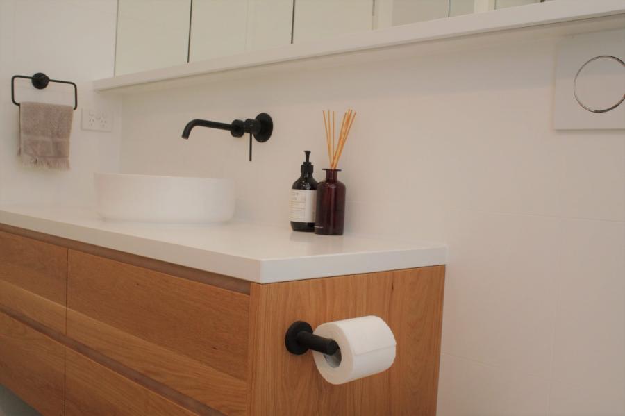 Timber bathroom vanity with white basin, matte black tapware and toilet roll holder