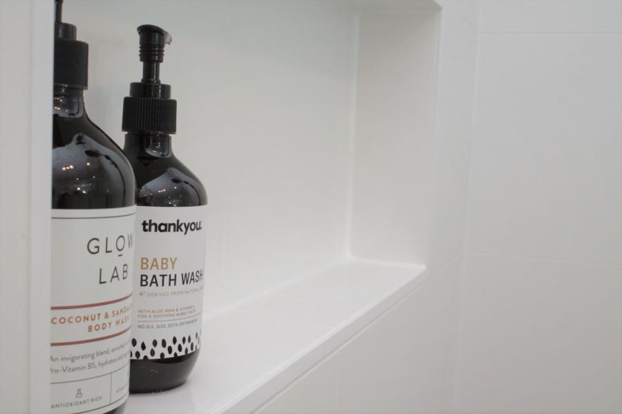 Close-up of bath wash bottles on a white recessed bathroom shelf