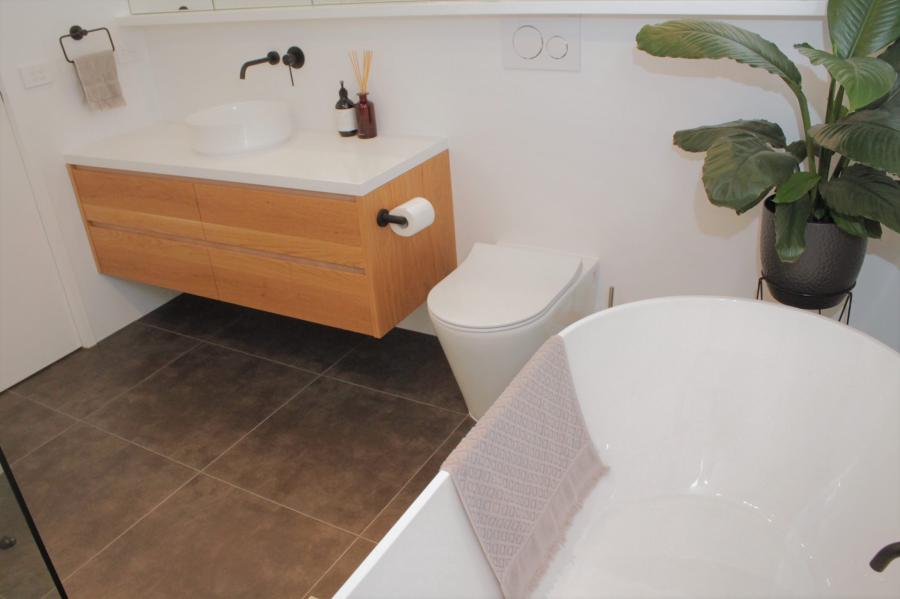 Modern bathroom with timber vanity, freestanding bath and floor-mounted toilet