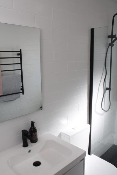Modern white bathroom vanity with black tapware, mirror, heated towel rail and walk-in shower