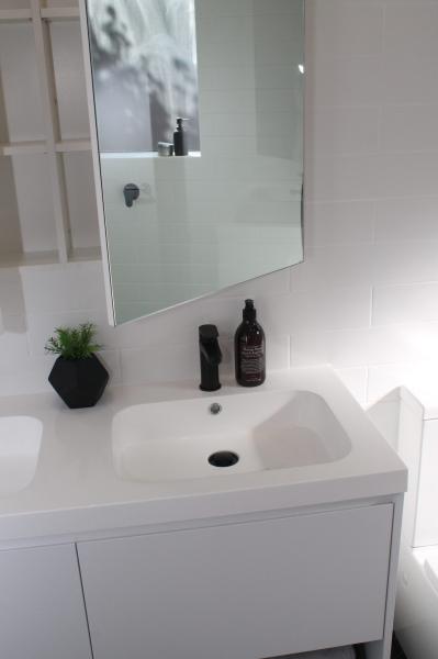 Modern white bathroom vanity with basin, mirror cabinet and black accessories