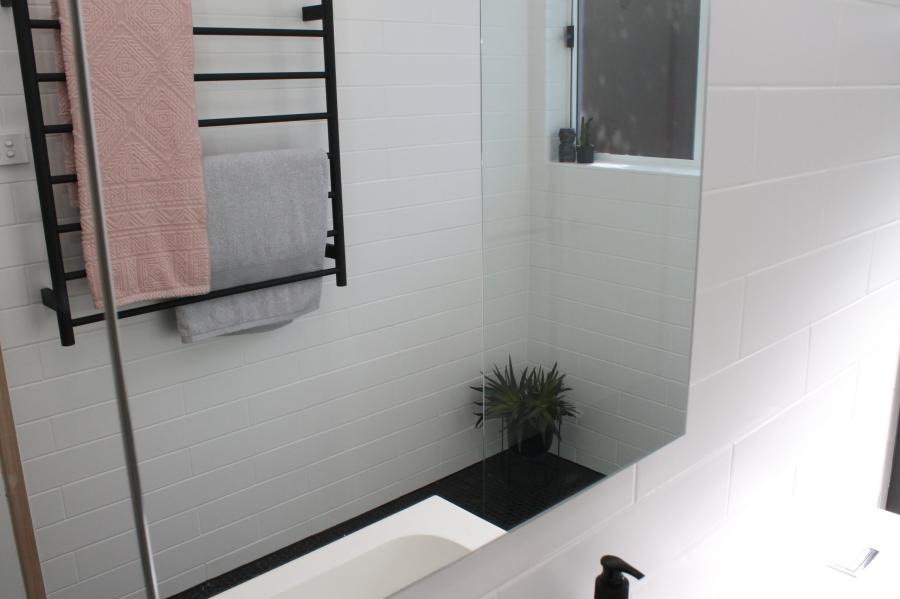 Modern white bathroom with black towel rail, vanity and shower screen