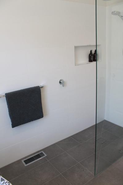 Walk-in shower with frameless glass screen, wall niche and grey floor tiles